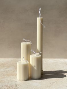 three white candles sitting next to each other on a table