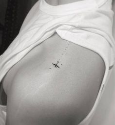 an airplane tattoo on the back of a woman's left shoulder