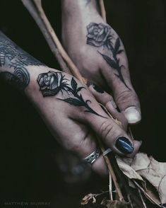 black and white photo of two hands with tattoos on them holding each other's fingers