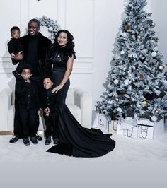 a family poses in front of a christmas tree