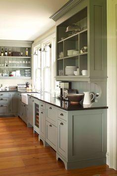 a large kitchen with gray cabinets and wood floors is pictured in this image from the front view