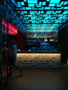 a person walking in front of a bar with blue lights on the ceiling and shelves