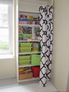 an organized pantry in the corner of a room with white walls and black and white curtains