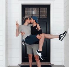 two people are kissing in front of a black door