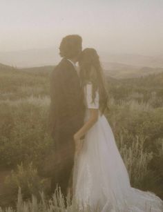 a bride and groom kissing in the field