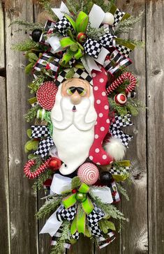 a christmas wreath hanging on the side of a wooden fence with a santa claus face