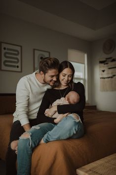 a man and woman sitting on top of a bed holding a baby