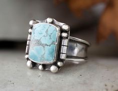 "The setting is a Cushion 15mm x 11mm Sand Hill Turquoise Cabochon that is in a Bezel setting accented with beads and triangle wire. This stone is opaque and is light blue with gray matrix. At its widest the shank is 3/8\" then narrows to 1/8\" for a comfortable fit. This ring cannot be resized. Size 11 Sand Hill Turquoise, natural stone, Sterling Silver Statement Ring, Handmade jewelry. This chic cocktail ring has been handmade using the purest 925 Sterling Silver that has been fused, stamped and lightly oxidized. This is a one of a kind chunky ring perfect for the chic jewelry wearer that wants that southwest jewelry vibe. It is an eye popping ring that will catch the attention of western jewelry lovers. Sand Hill Turquoise is becoming harder and harder to find as the mine from which it Western Boho Chic, Thick Silver Ring, Western Rings, Town Outfits, Turquoise Statement Ring, Chunky Ring, Southwest Jewelry, Square Stone, Jewelry Metal