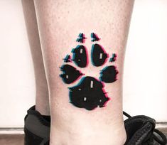 a dog paw tattoo on the leg with pink and blue ink in it's center