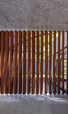 an open room with wooden slats on the wall and concrete flooring in front of it