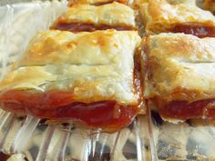 several pastries sitting on top of a plastic tray covered in cheese and tomato sauce