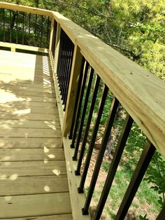 a wooden deck with black railings in the woods