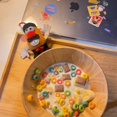 a bowl filled with cereal sitting on top of a table next to a stuffed animal