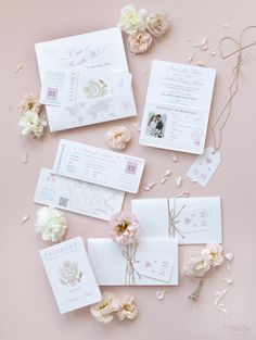 the wedding stationery is laid out on a pink surface with flowers and petals around it