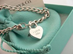 Offered for sale is a wonderful and rare Tiffany and Co. Sterling Silver "I Love You" Heart Padlock bracelet. The piece is made from substantial and bright Tiffany silver, and yet retains a very feminine feel to it. Attached to its very substantial Tiffany Silver Textured charm bracelet is a Heart padlock charm with "I Love You" written in beautiful script. The "I Love You" heart padlock charm opens and closes and thus can be used as a charm on a necklace or as part of another charm bracelet! Su Luxury White Gold Bracelets For Valentine's Day, Luxury Sterling Silver Bracelets For Valentine's Day, Luxury Sterling Silver Heart Bracelet For Gift, Luxury Sterling Silver Heart Bracelet For Anniversary, Luxury Heart Charm Bracelet For Anniversary, Luxury Chain Bracelet With Sterling Silver Clasp As Gift, Luxury Heart Charm Bracelet Gift, Luxury Heart Cut Bracelet As Gift, Luxury Heart Cut Bracelet For Gift