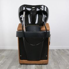 a black and brown chair sitting on top of a hard wood floor next to a white wall