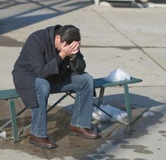 a man sitting on a bench with his head in his hands