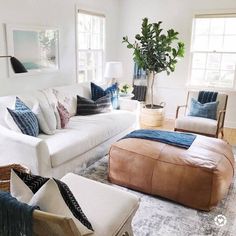 a living room filled with white furniture and lots of pillows on top of it's couches