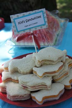 a red plate topped with sandwiches on top of a blue table cloth covered in candy