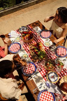 two people sitting at a picnic table with plates and bowls of food on the table