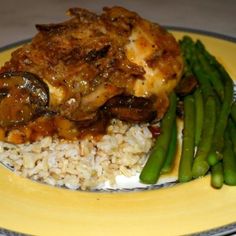 a yellow plate topped with rice and meat covered in gravy next to asparagus