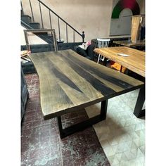 a wooden table sitting in the middle of a living room next to a stair case