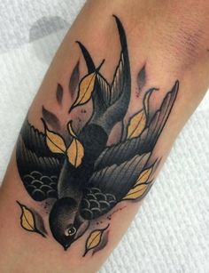 a black bird with yellow leaves on it's wings is sitting on the arm