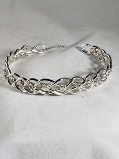 "Beautiful braided Celtic pattern siIver wire flexible bracelet. This bracelet is appropriate for ladies or men. It is made from Argentium silver wire, 14 gage for strength with a hook closure. Argentium has an alloy that allows it to be tarnish free much longer than sterling silver, is brighter, and as a bonus is hypo allergenic. It is 9\" in circumference and with the hook is more like a bangle than a cuff. With the 14 gauge wire, this bracelet is quite rigid and will not easily bend out of shape." Silver Sterling Braided Bracelets, Silver Braided Bangle Bracelets, Silver Hand Wrapped Braided Bangle Bracelet, Sterling Silver Wire Wrapped Bangle Bracelet, Silver Wire Wrapped Cuff Bracelet Gift, Elegant Silver Hand-wrapped Braided Bracelet, Elegant Silver Wire Wrapped Cuff Bracelet, Silver Braided Hand-wrapped Bangle Bracelet, Silver Hand-wrapped Braided Bangle Bracelet