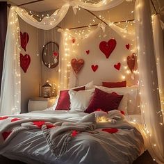 a white bed with red pillows and lights on the headboard, in a bedroom decorated for valentine's day