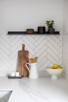 a white kitchen counter top with cutting board, bowl and lemons on the counter