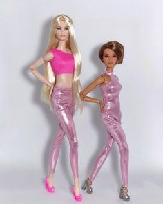 two barbie dolls standing next to each other