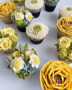 cupcakes decorated with yellow and white flowers are arranged in a circle on a table