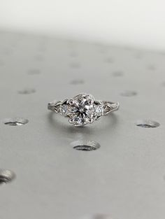 an engagement ring with three stones in the center on top of a silver surface surrounded by dots