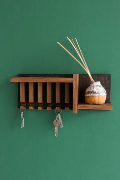 a wooden shelf with key hooks and a vase on it, hanging from the wall