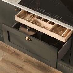 an open drawer with utensils and pans in it on top of a counter