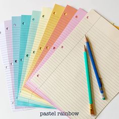 several lined notebooks and a pen sitting on top of each other with the words pastel rainbow written below them