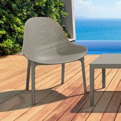 two chairs and a table on a wooden deck overlooking the ocean with a pool in the background