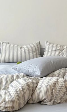 an unmade bed with striped sheets and pillows