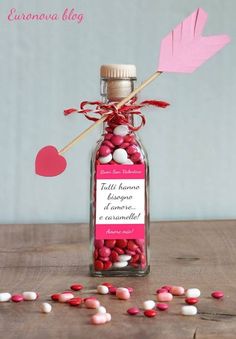 a bottle filled with candy sitting on top of a table next to hearts and an arrow