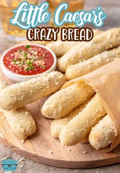 some bread sticks are on a wooden plate with dipping sauce in the background and text overlay that reads little caesar's crazy breadsticks