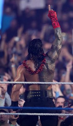 the wrestler is holding his fist up as he stands in front of an audience