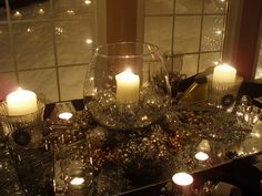 a table topped with lots of candles next to a large window filled with windowsills