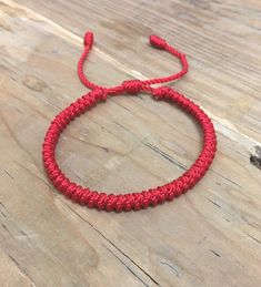 a red rope bracelet on top of a wooden table