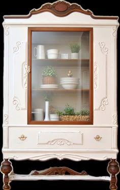 an old fashioned china cabinet with plants and dishes on the shelves in front of it