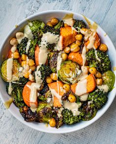 a white bowl filled with broccoli, carrots and chickpeas covered in dressing