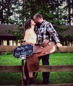 a man and woman kissing in front of a horse saddle