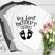 two t - shirts with the words my first mother's day on them next to flowers