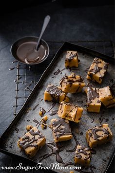 chocolate and peanut butter fudges on a baking sheet with a bowl of milk