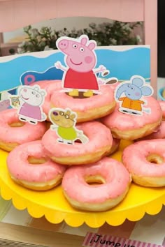 there are many pink donuts on the yellow plate with peppa pig stickers