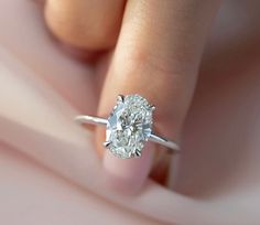 a woman's hand holding a ring with a diamond in it and the center stone is white gold